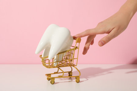 A tooth in a shopping cart on a pink background.の写真素材