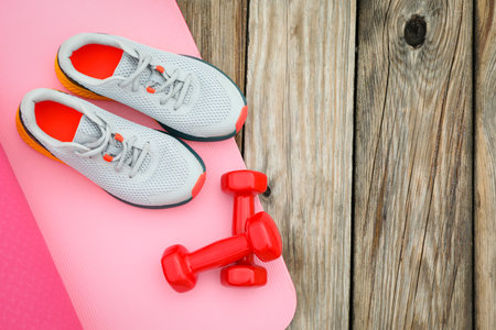 Karemat, sneakers and dumbbells on wooden background, space for textの写真素材