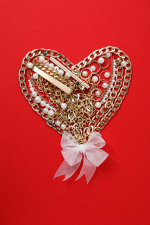 Heart made of jewelry on a red background.の写真素材