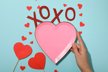 Plate in hand and paper hearts on blue background, top viewの写真素材