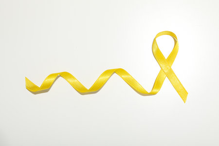Yellow satin ribbon on a white backgroundの写真素材