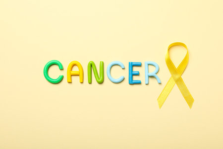The inscription Cancer in colorful letters with a yellow ribbonの写真素材