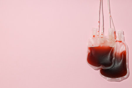 Bags with donor blood on pink background, space for textの写真素材