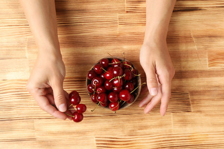 Ripe cherry fruits in a bowl on a wooden backgroundの写真素材