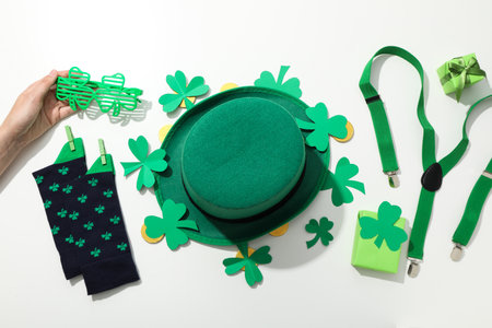 Accessories, golden coins, hand and paper clover leaves on white background, top view