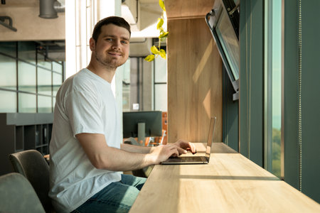 A cheerful young entrepreneur works in a modern workspace
