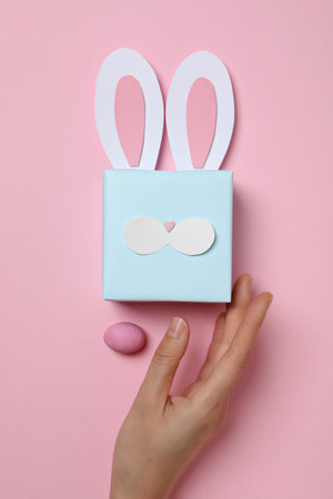Blue gift box with rabbit ears on pink background