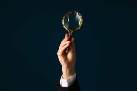 A businessman's hand holds a magnifying glass
