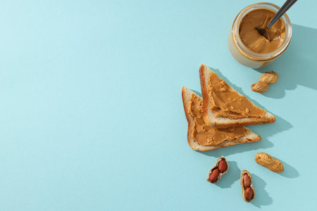 Peanut paste in a glass jar with toast, on a light background.の写真素材