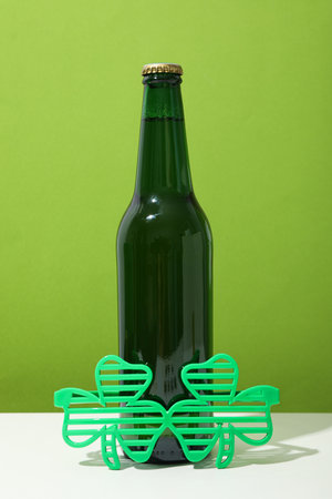 Green bottle and glasses on white table on green backgroundの写真素材