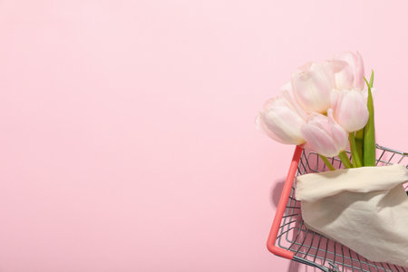 Tulips in cotton bag in shopping basket on pink background, space for textの写真素材