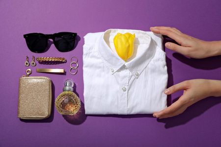 Female shirt, hands and accessories on purple background, top viewの写真素材