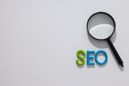 Letters SEO and magnifying glass on light background, space for text