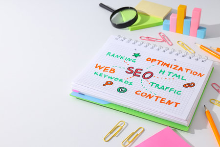 Notepad with diagram, magnifying glass and stationery on white background, space for textの写真素材