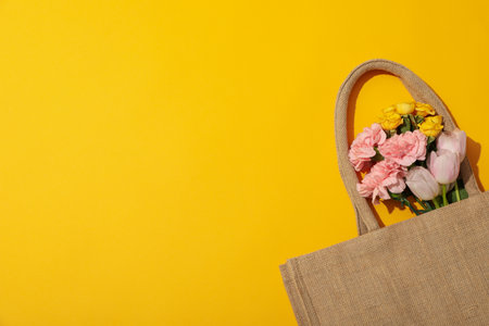 Flowers in bag on yellow background, space for textの写真素材
