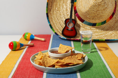 Nachos with sombrero and tequila on a light background