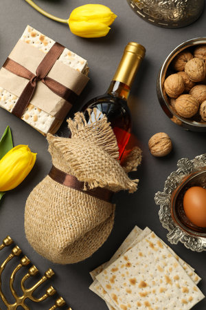 Matzo, nuts, hanukkiah, bottle of wine and flowers on gray background, top view