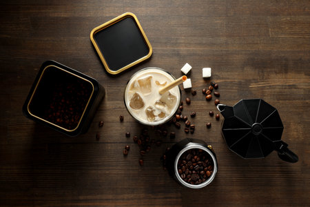 Glass with iced coffee drink, coffee maker, coffee bean and sugar on wooden background, top viewの写真素材
