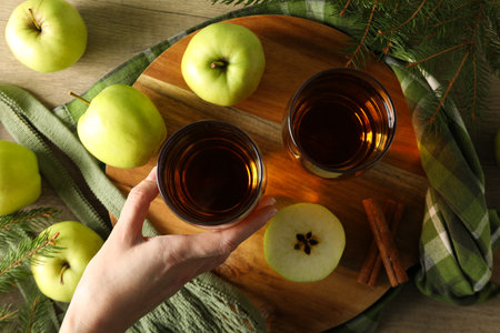 Glasses with apple cider, hand, bag with green apples on board on wooden background, top viewの写真素材