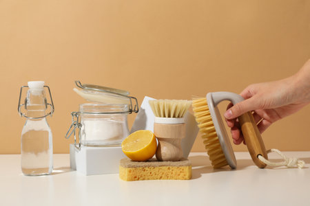 Sponge, brushes, hand and natural detergent ingredients on beige background