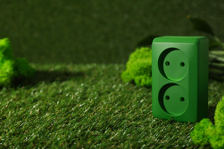 Green electrical socket on the grass, eco house concept