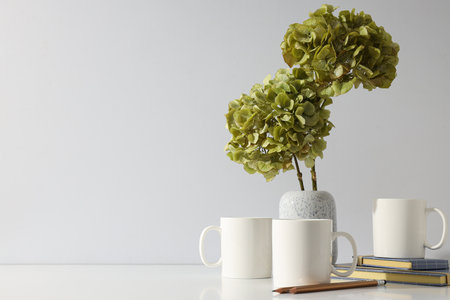 White cups with green hydrangeas in a vaseの写真素材