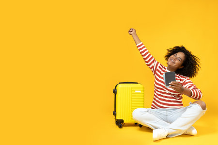 An African-American woman with a suitcase and a passport in her handsの写真素材