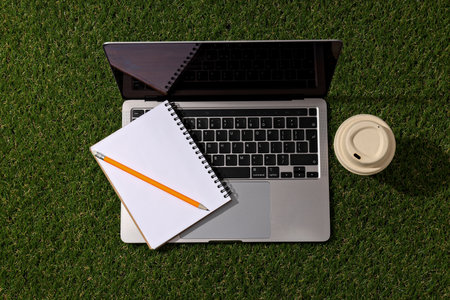 Laptop with notebooks on the grass, top view.の写真素材
