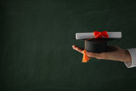 Miniature graduate hat and diploma, in hands.の写真素材