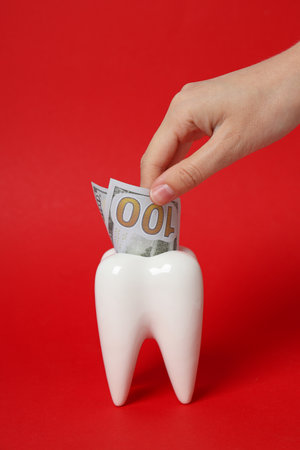 Cash in tooth and hand on red backgroundの写真素材