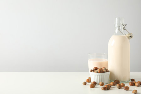 Bottle and glass with milk, bowl with nuts on white background, space for textの写真素材