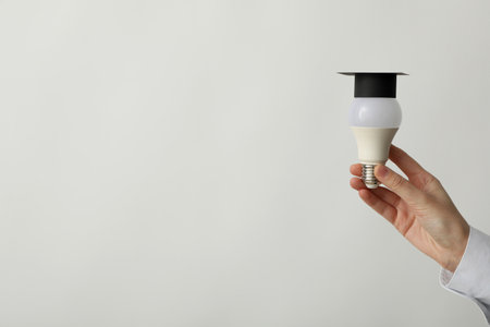 A university graduate hat on a light bulb, on a gray background.の写真素材