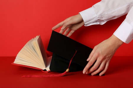 Graduate hat and books, on a red background.の写真素材