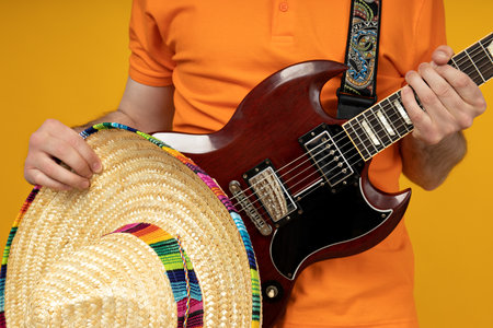 Attractive young guy playing guitar in Mexican hatの写真素材