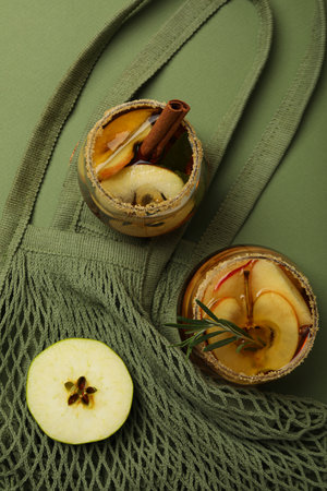 Glasses with apple cider and apple slice on bag on green background, top viewの写真素材