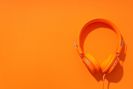 On-top, large, bright orange headphones, on a light background.の写真素材