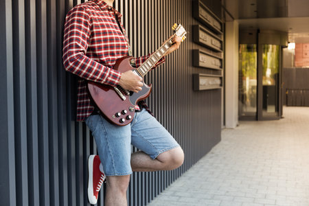 Stylish young guy playing guitar on the street