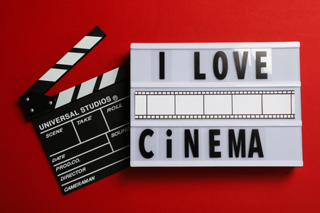 Light box with text and clapperboard on red background, top view