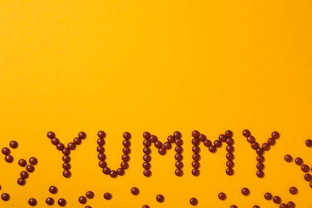 The word: "yummy" laid out from candies on a green background.の写真素材