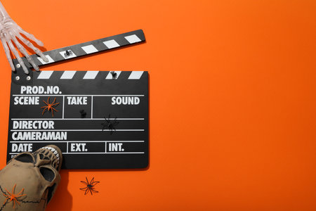 Clapperboard and Halloween decorations on orange background, space for textの写真素材