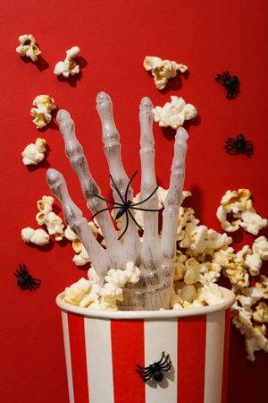 Paper cup with popcorn and Halloween decorations on red background, close upの写真素材