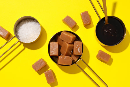 Cubes of salted caramel with salt on a yellow backgroundの写真素材