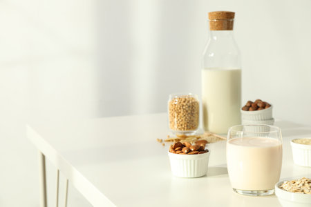 Bottle and glass of alternative milk and herbal ingredients on light background, space for textの写真素材