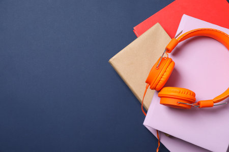 Books with modern headphones, on a blue background.