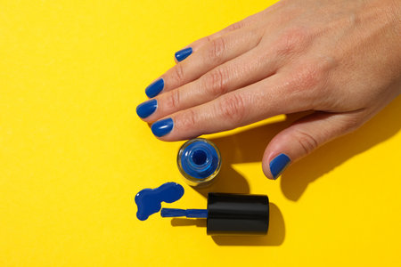 Blue nail polish on a yellow backgroundの写真素材