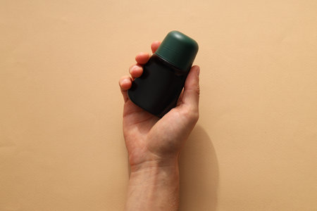 Cosmetic jar in hand on beige background, top viewの写真素材