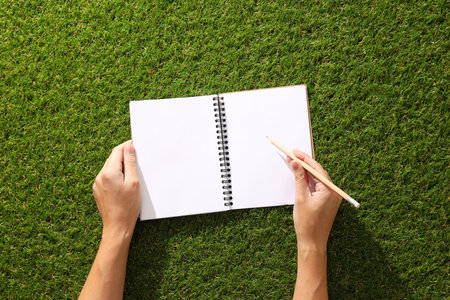 A paper notebook with a pencil on the grass.の写真素材