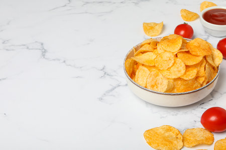 Potato chips in a bowl with sauce and tomatoes on a light backgroundの写真素材