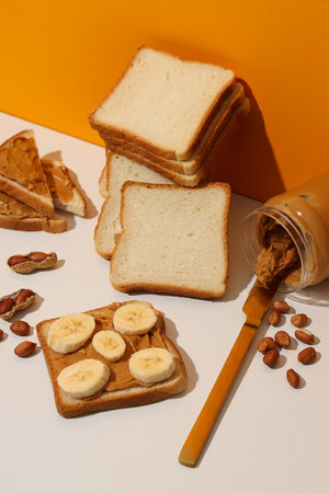 Peanut paste in a glass jar with toast, on a light background.