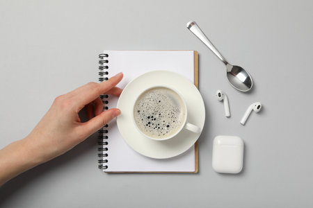 A cup of coffee with headphones and a notebook on a light backgroundの写真素材